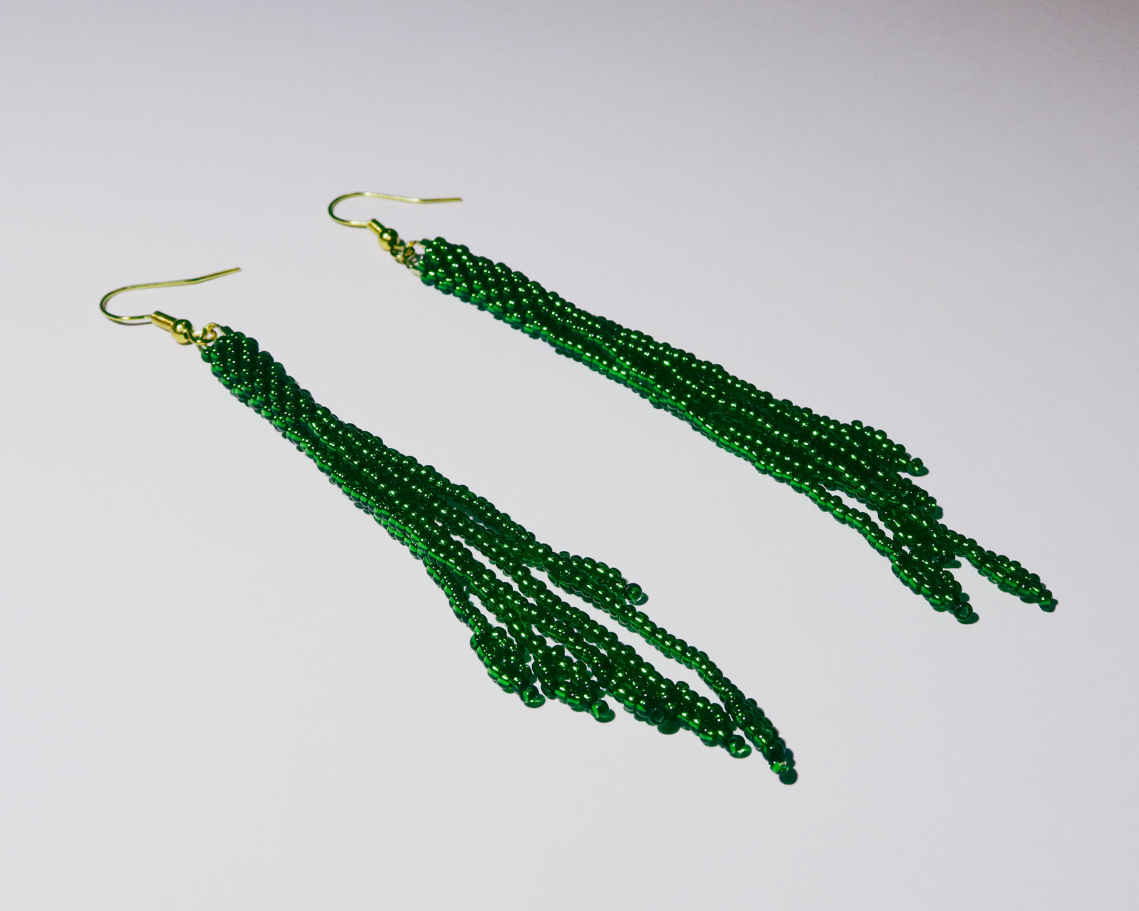 Green beaded earrings on a light gray background