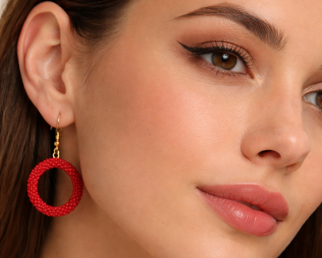 Close-up of a woman wearing red hoop earrings with a neutral background