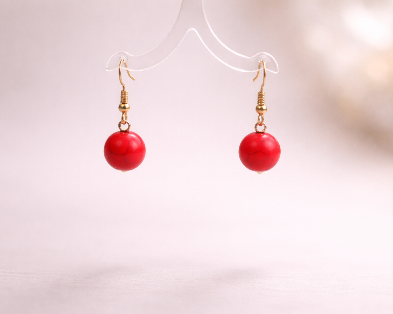 Red spherical earrings on a white background