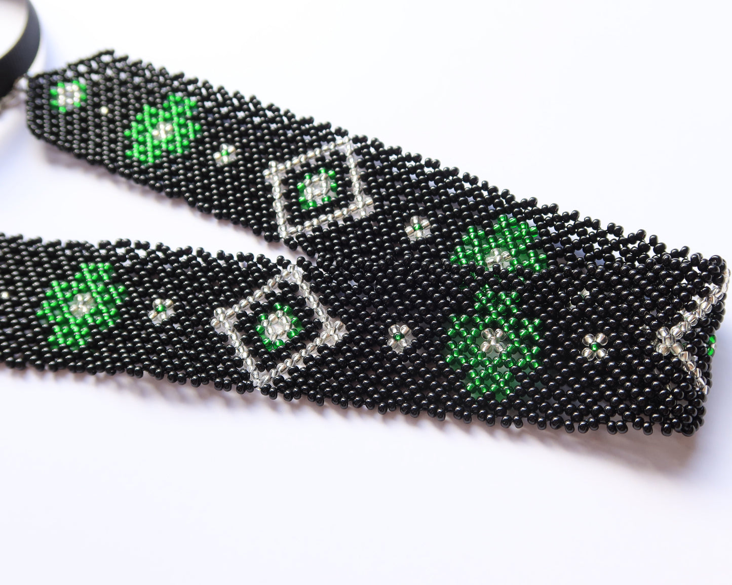 Black beaded earrings with green accents on a white background