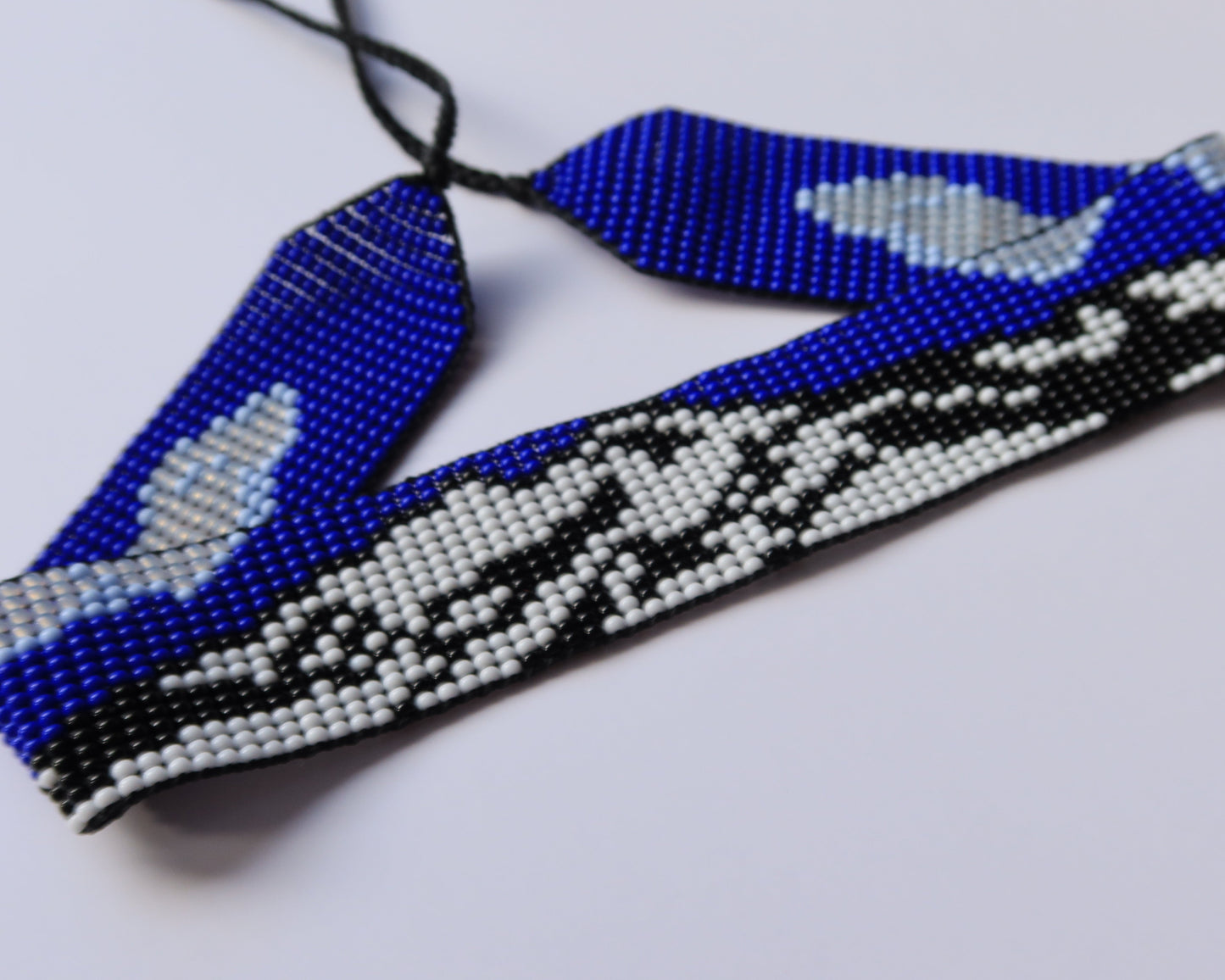 Beaded headband with blue, white, and black pattern on a light gray background