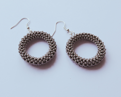 Pair of round beaded earrings on a light purple background