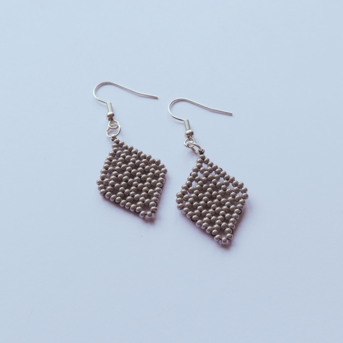 Pair of beaded heart-shaped earrings on a light purple background
