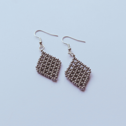 Pair of beaded heart-shaped earrings on a light purple background