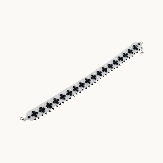 Bracelet with black clover-shaped beads on a white background
