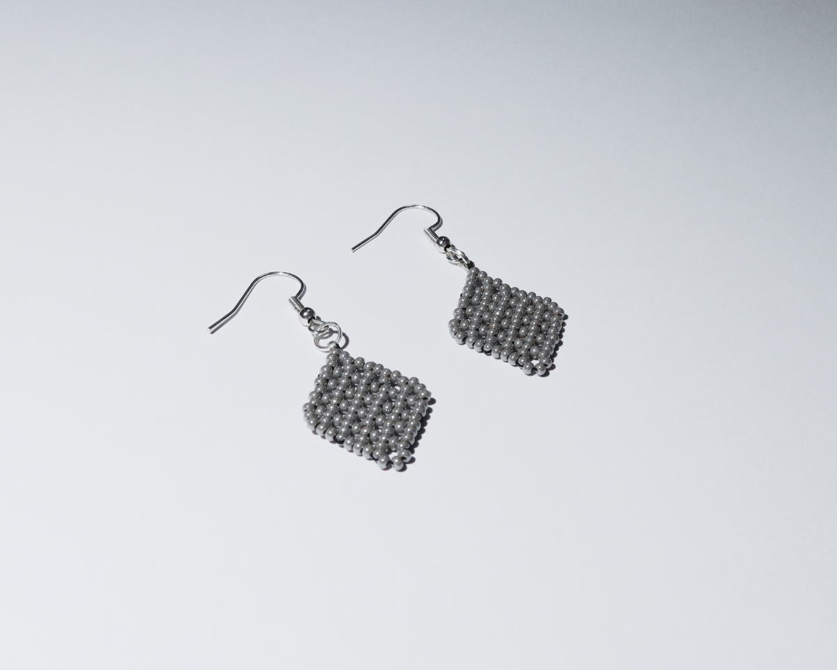 Pair of silver beaded earrings on a light gray background