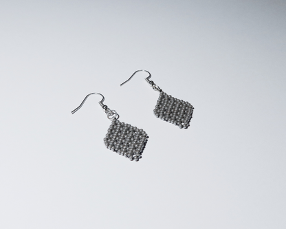 Pair of silver beaded earrings on a light gray background