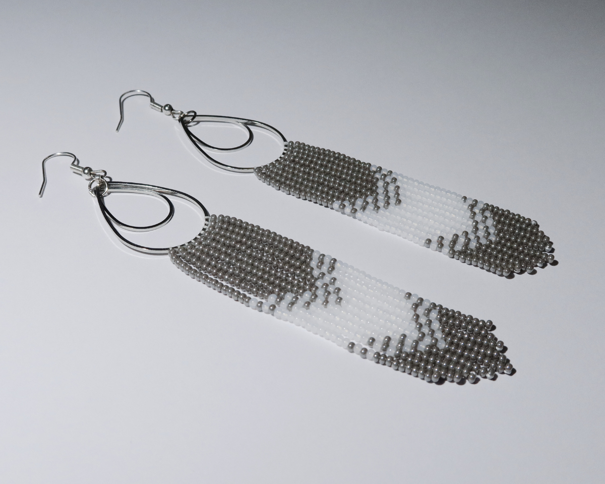 Pair of silver beaded tassel earrings on a light gray background
