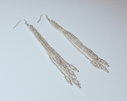 Pair of silver fringe earrings on a light gray background