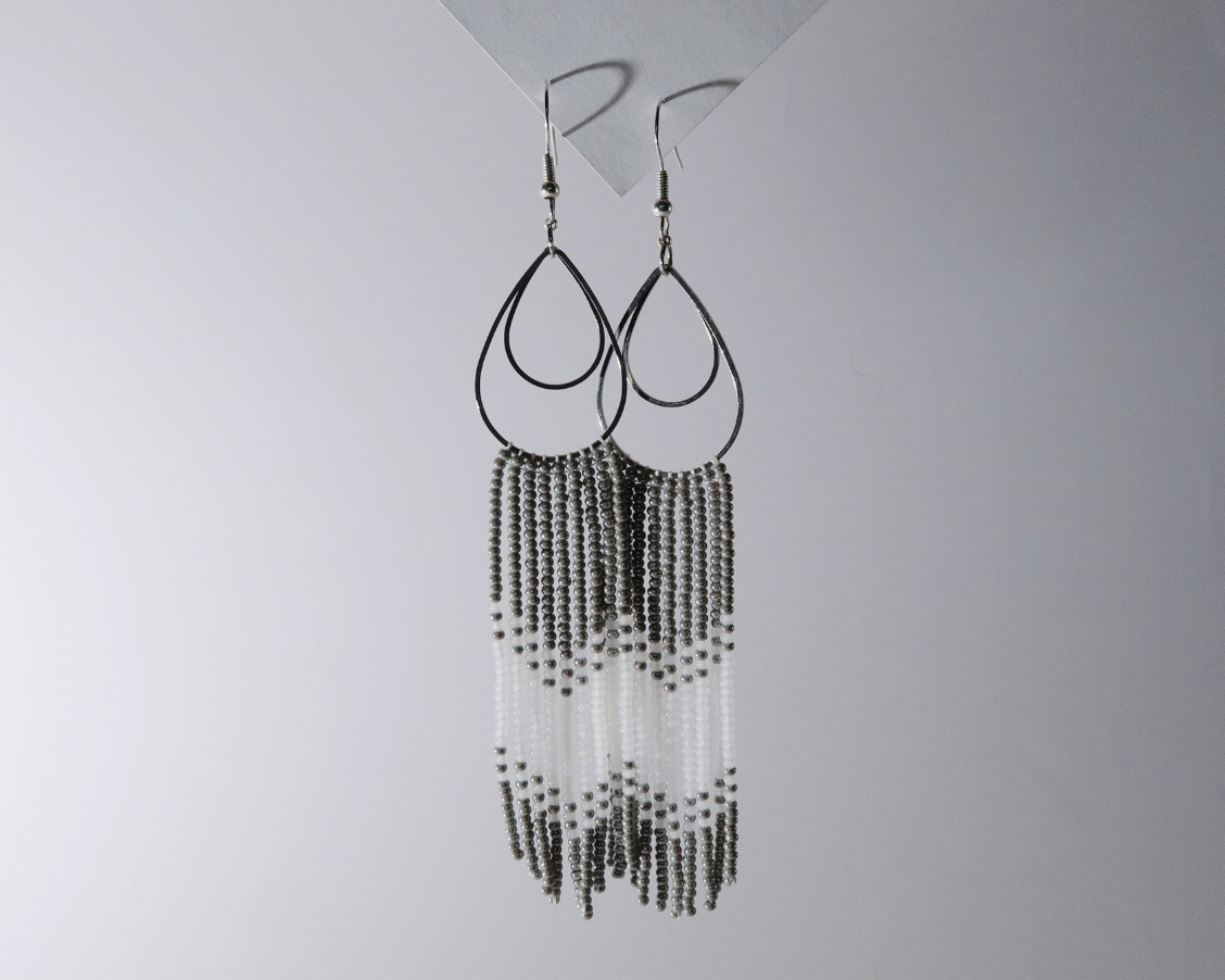 Beaded earrings hanging against a plain background