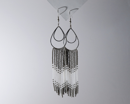 Beaded earrings hanging against a plain background