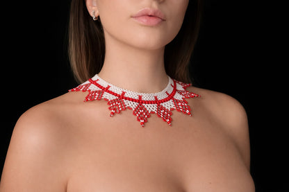 Red and white beaded necklace worn by a model on a black background