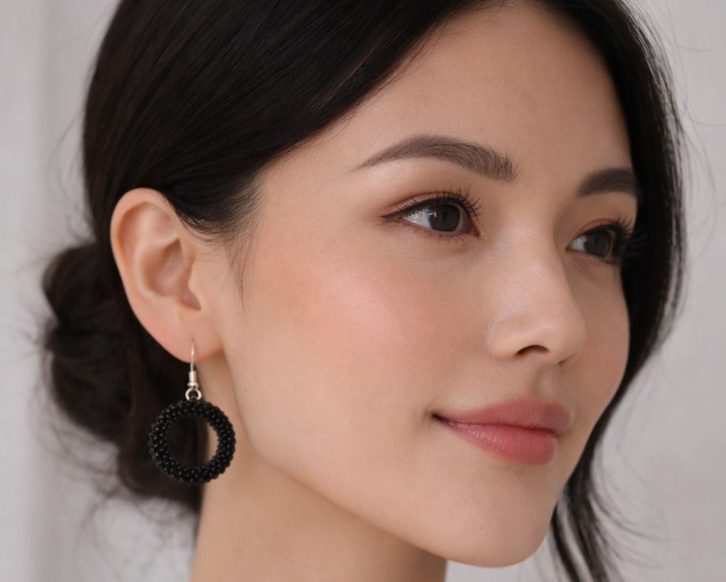 Woman wearing a black hoop earring against a white background
