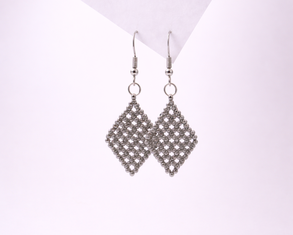 Pair of silver diamond-shaped earrings on a light purple background
