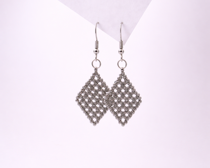 Pair of silver diamond-shaped earrings on a light purple background