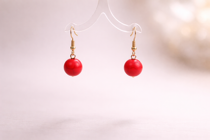 Red spherical earrings on a white background