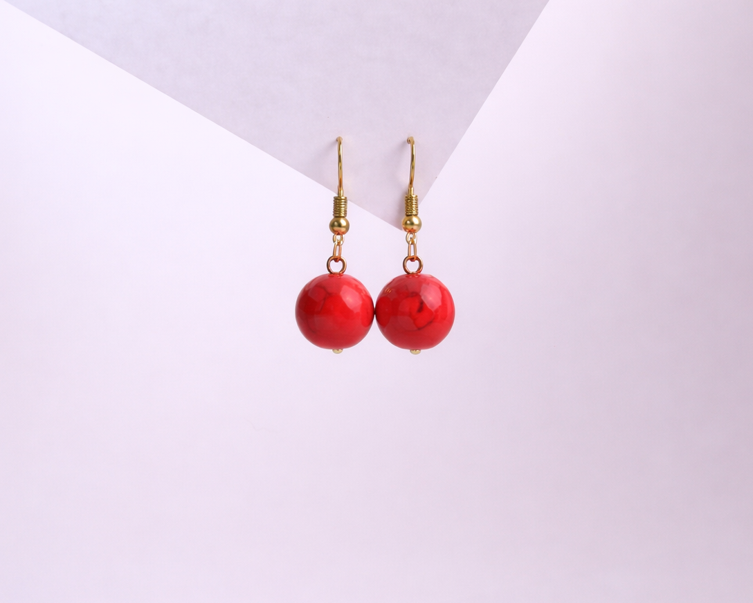 Red earrings with gold hooks on a white background
