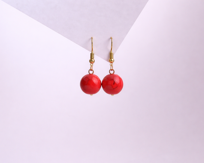 Red earrings with gold hooks on a white background