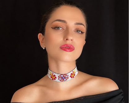 Comely UA white beaded choker with red, blue, and yellow floral motifs. Adjustable ties with tassels.
