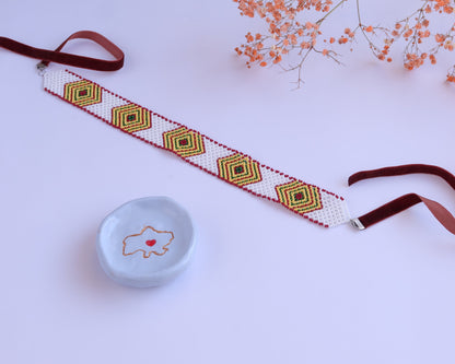 Comely UA white beaded choker with diamond pattern in green, yellow, and red, featuring velvet ribbons.