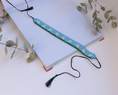 Comely UA beaded gerdan with white hares on blue sky and green grass pattern, adjustable ties with tassels.