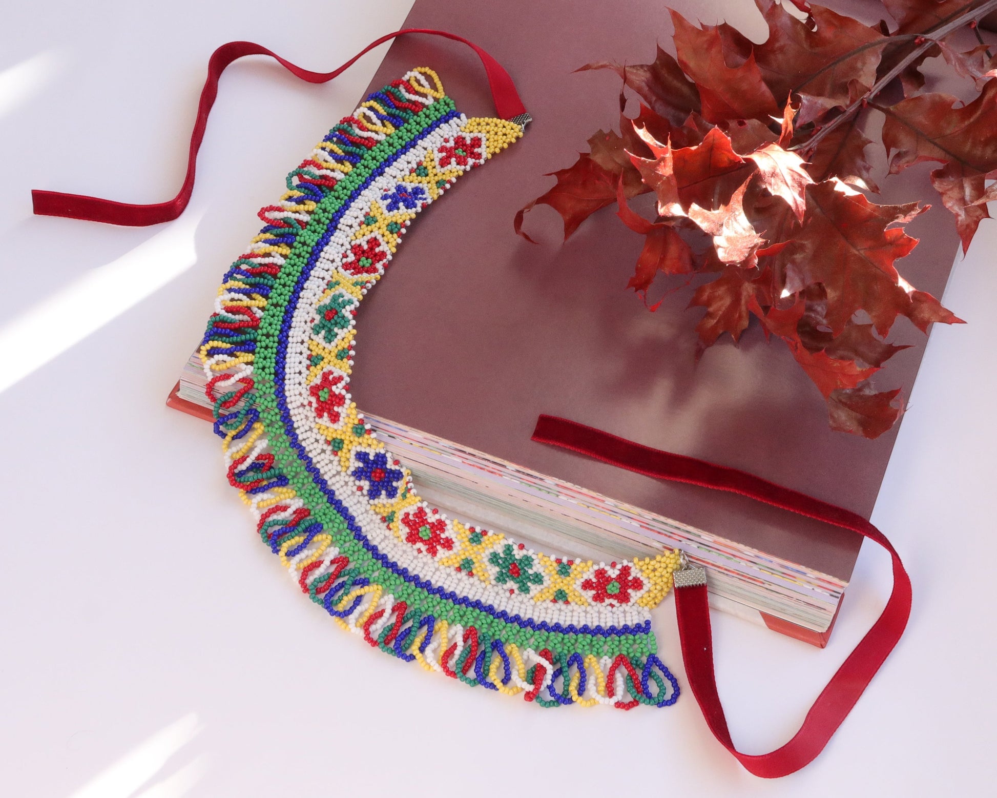 Comely UA beaded silyanka necklace with floral motifs in yellow, green, red, blue, and white. Features fringed border and red velvet ribbons.