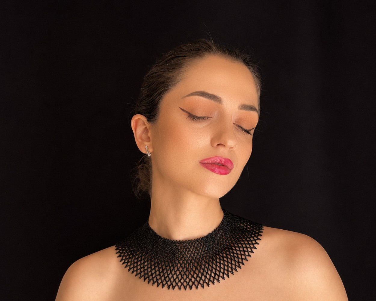 Comely UA black beaded silyanka necklace, a flat woven choker with a diamond pattern, worn by a woman with closed eyes.