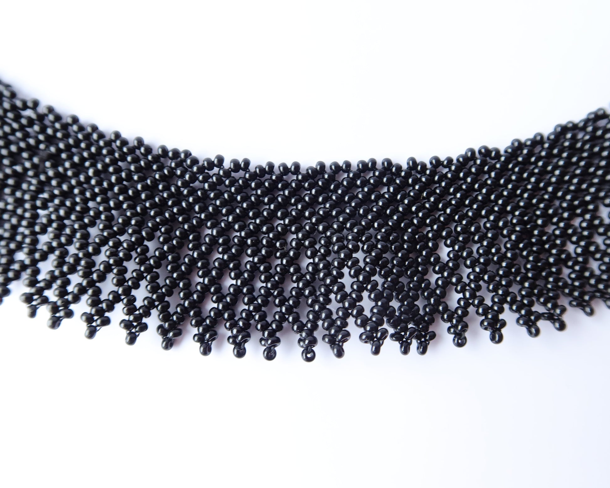 Comely UA black beaded necklace, a flat woven choker with a fringed hem, inspired by Ukrainian silyanka. Made of small black beads.