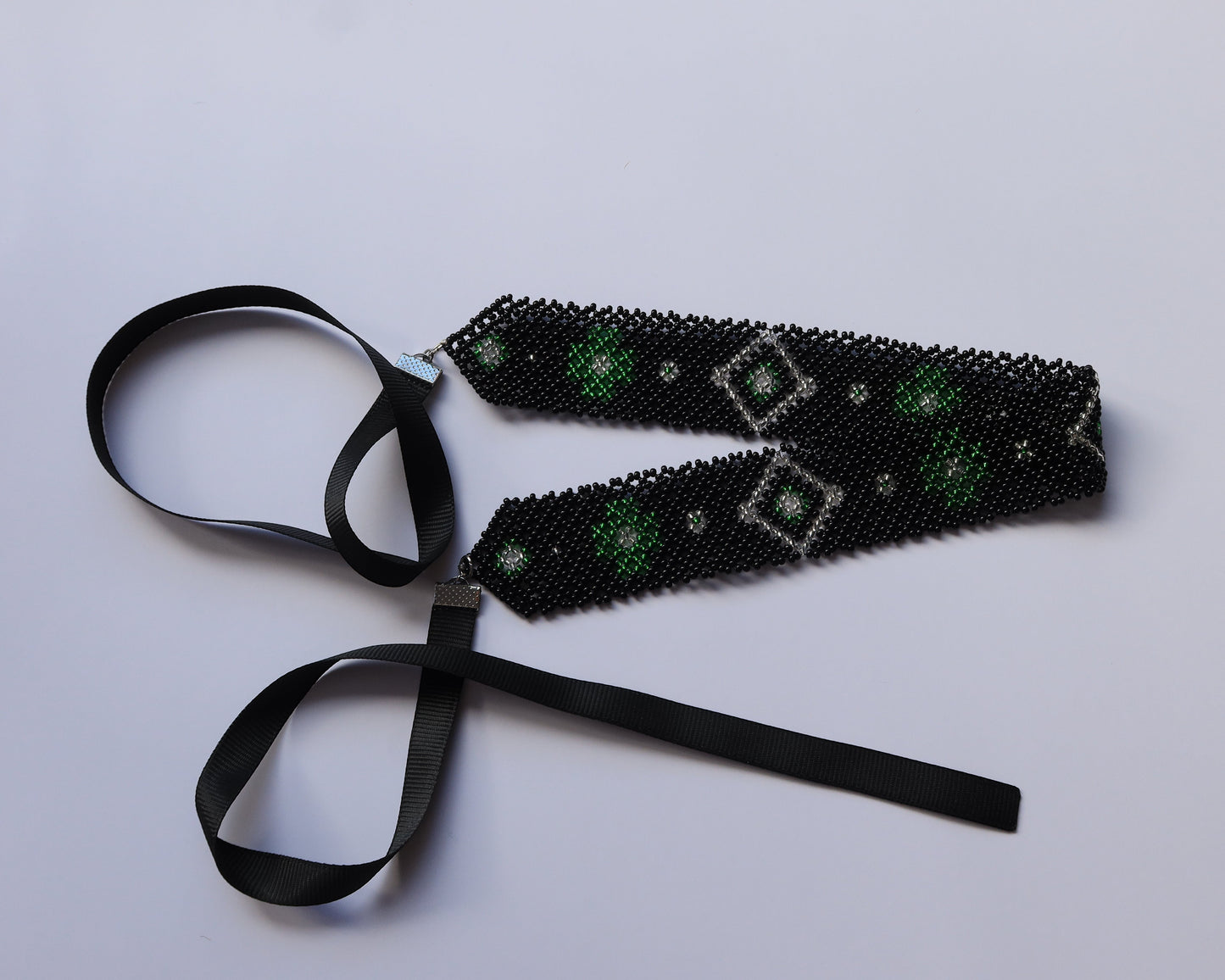Comely UA black beaded gerdan with green diamond pattern and silver accents. Features satin ribbons for adjustable fit.