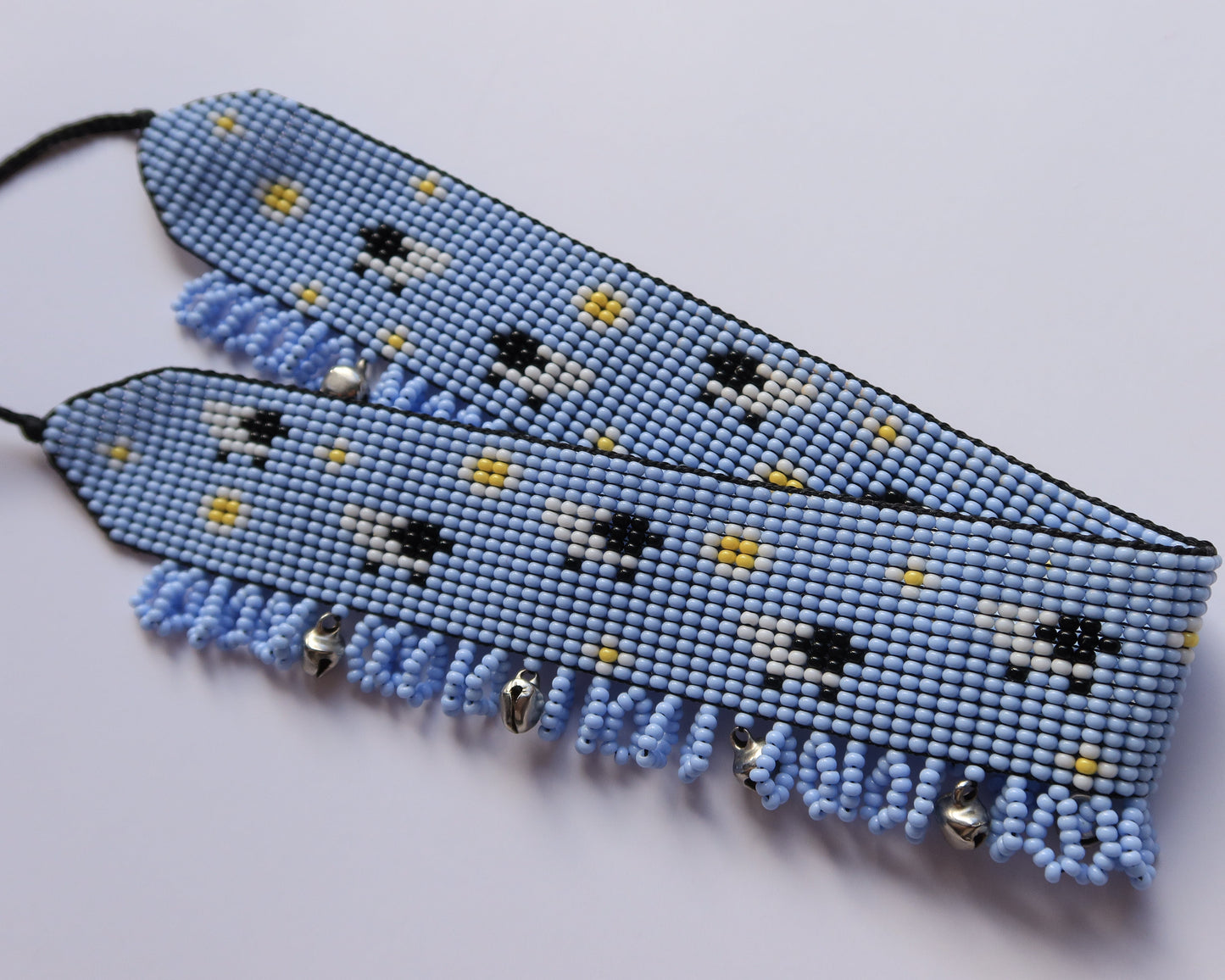 Comely UA light blue beaded gerdan with white daisies, yellow dots, and sheep motif. Features light blue fringe with silver bells.