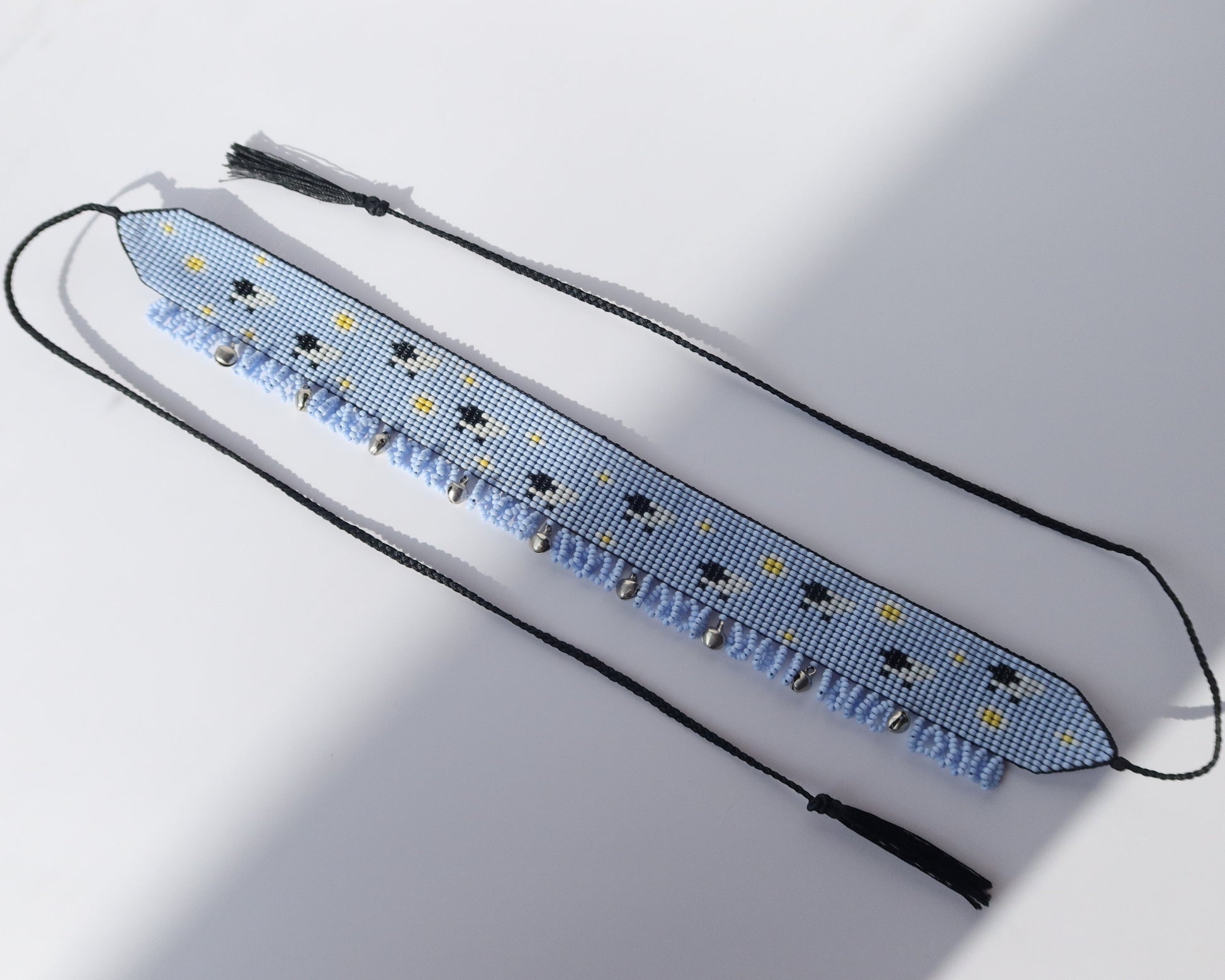 Comely UA sky-blue beaded gerdan with white daisies and sheep pattern, featuring light blue fringe and black tassels.