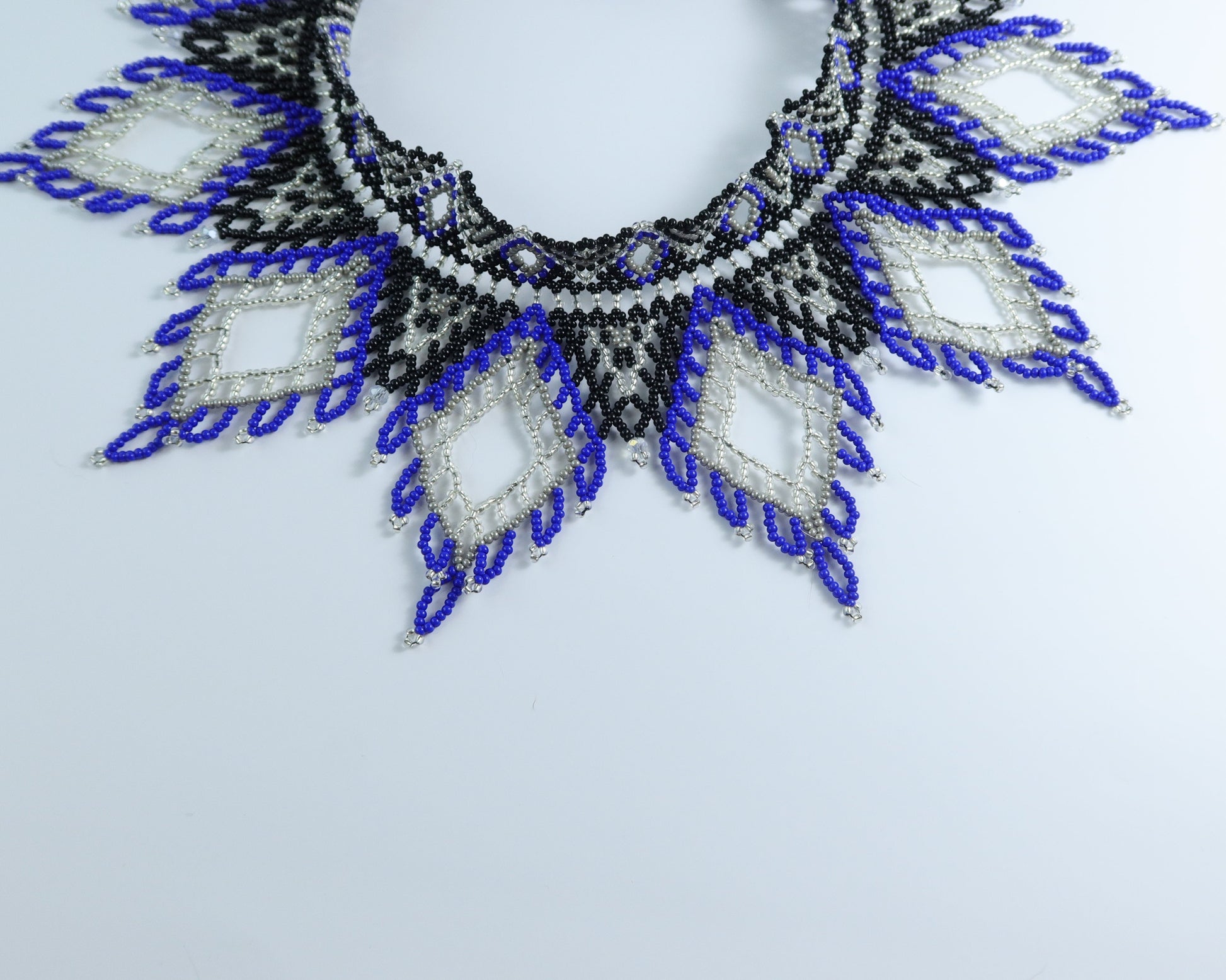 Comely UA Evian beaded necklace with blue, black, and silver diamond patterns. Czech seed beads, nylon thread, velvet ribbon ties.