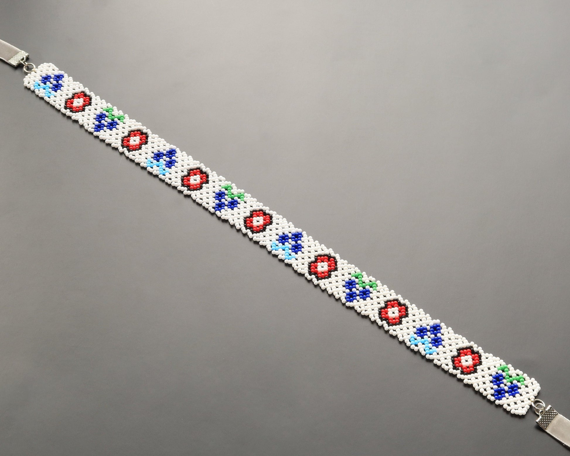 Comely UA white beaded gerdan necklace with red, blue, and green floral motifs. Adjustable velvet ribbon closure.