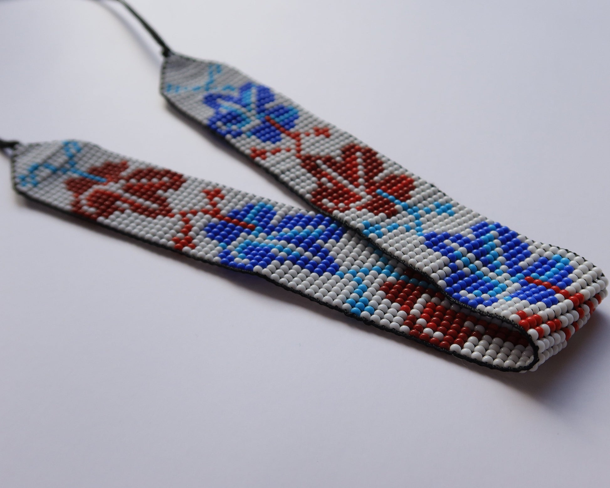 Comely UA beaded gerdan necklace with red and blue leaf pattern on white background. Czech seed beads.