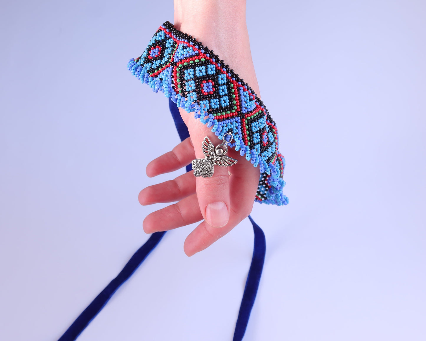 Comely UA Gerdan Luchka beaded collar with blue, black, red, and green geometric pattern and fringe. Features an angel pendant.
