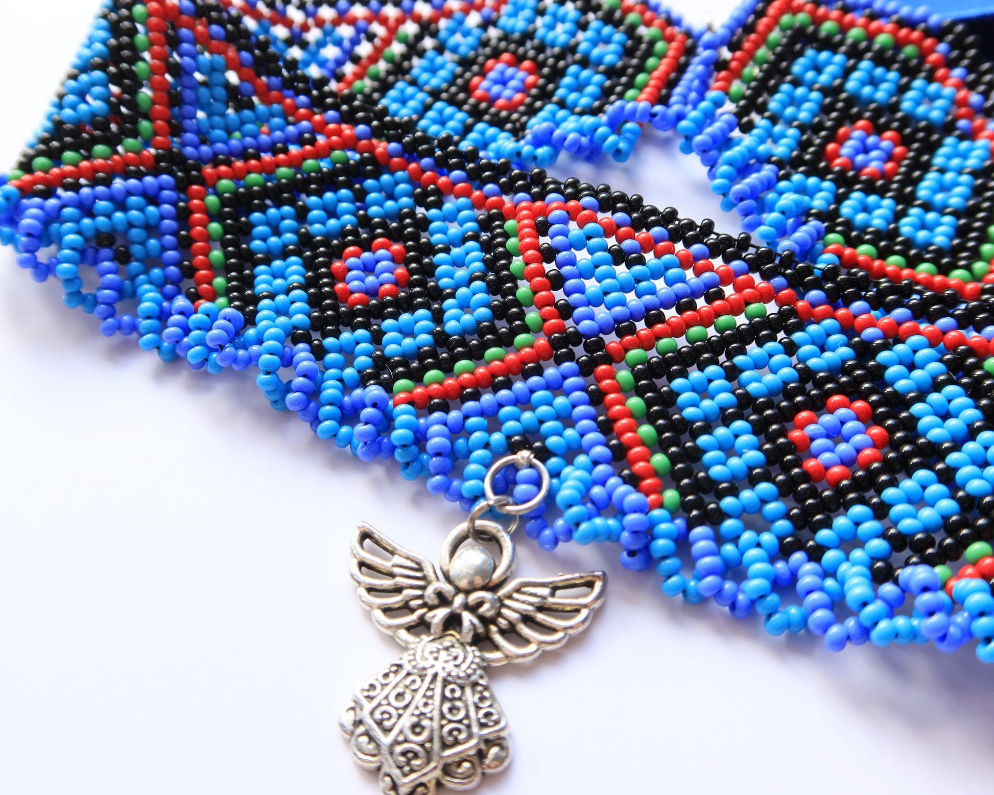 Comely UA Gerdan Luchka beaded necklace with blue, black, red, and green geometric pattern and angel pendant.
