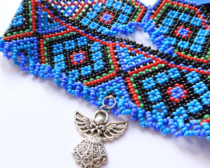 Comely UA Gerdan Luchka beaded necklace with blue, black, red, and green geometric pattern and angel pendant.