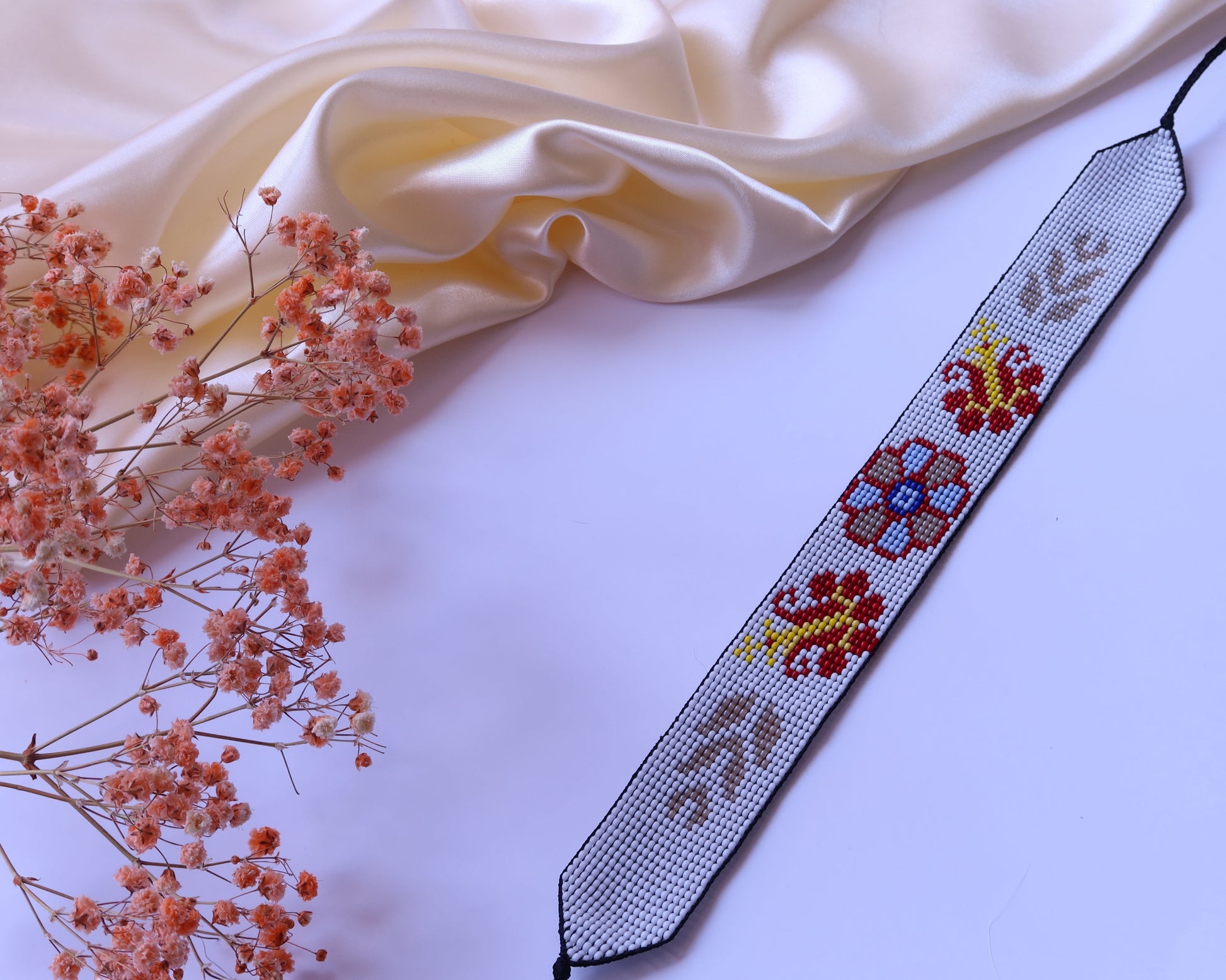Comely UA white beaded gerdan with red, yellow, and blue floral motifs and beige leaf accents. Adjustable ties.