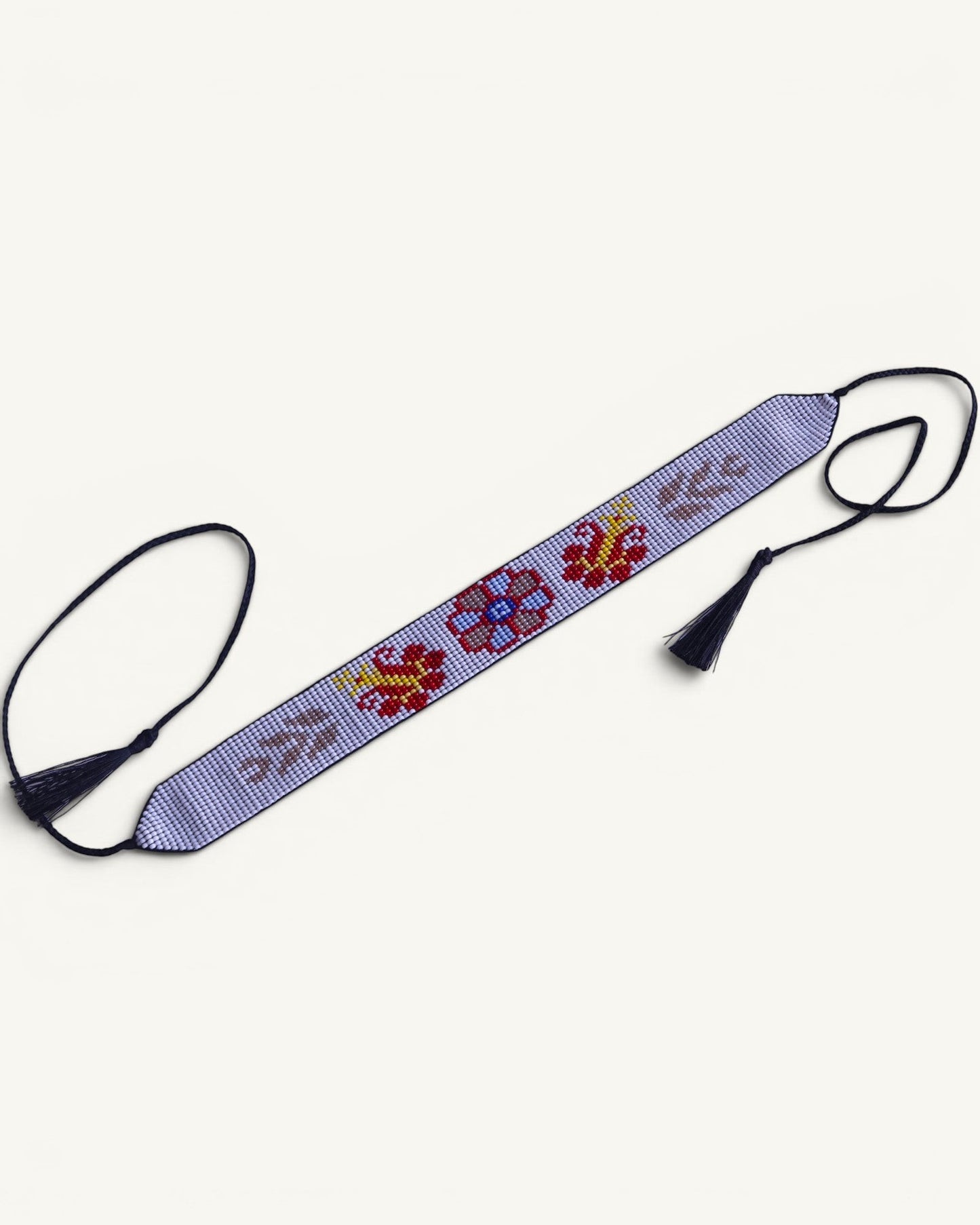 Comely UA Gerdan "Ornek" beaded choker with floral motifs in red, yellow, blue, and grey on a light purple background. Features adjustable ties with tassels.