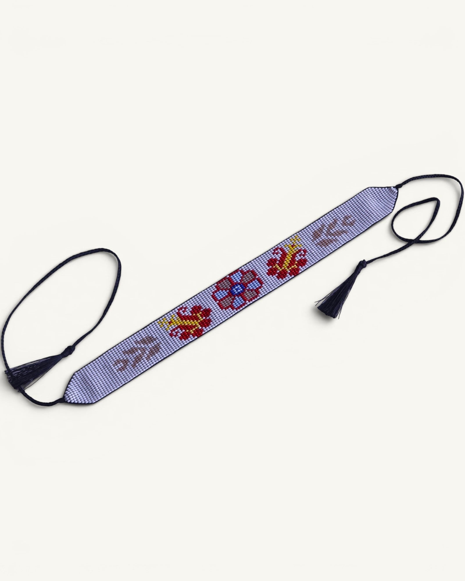 Comely UA Gerdan "Ornek" beaded choker with floral motifs in red, yellow, blue, and grey on a light purple background. Features adjustable ties with tassels.