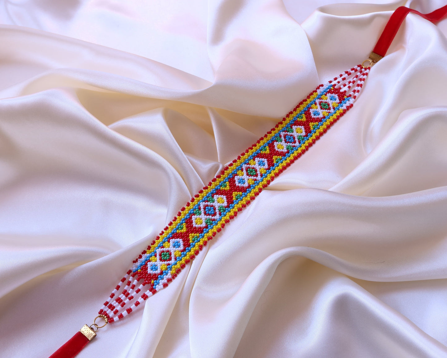 Comely UA Gerdan Khust Ornament beaded choker with red, yellow, blue, and white geometric diamond pattern on satin background.