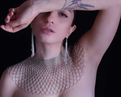 Comely UA "Living Net" kryvulka, a delicate beaded collar with silver and green Czech seed beads, inspired by Ukrainian lace. Woman wearing it with a black background