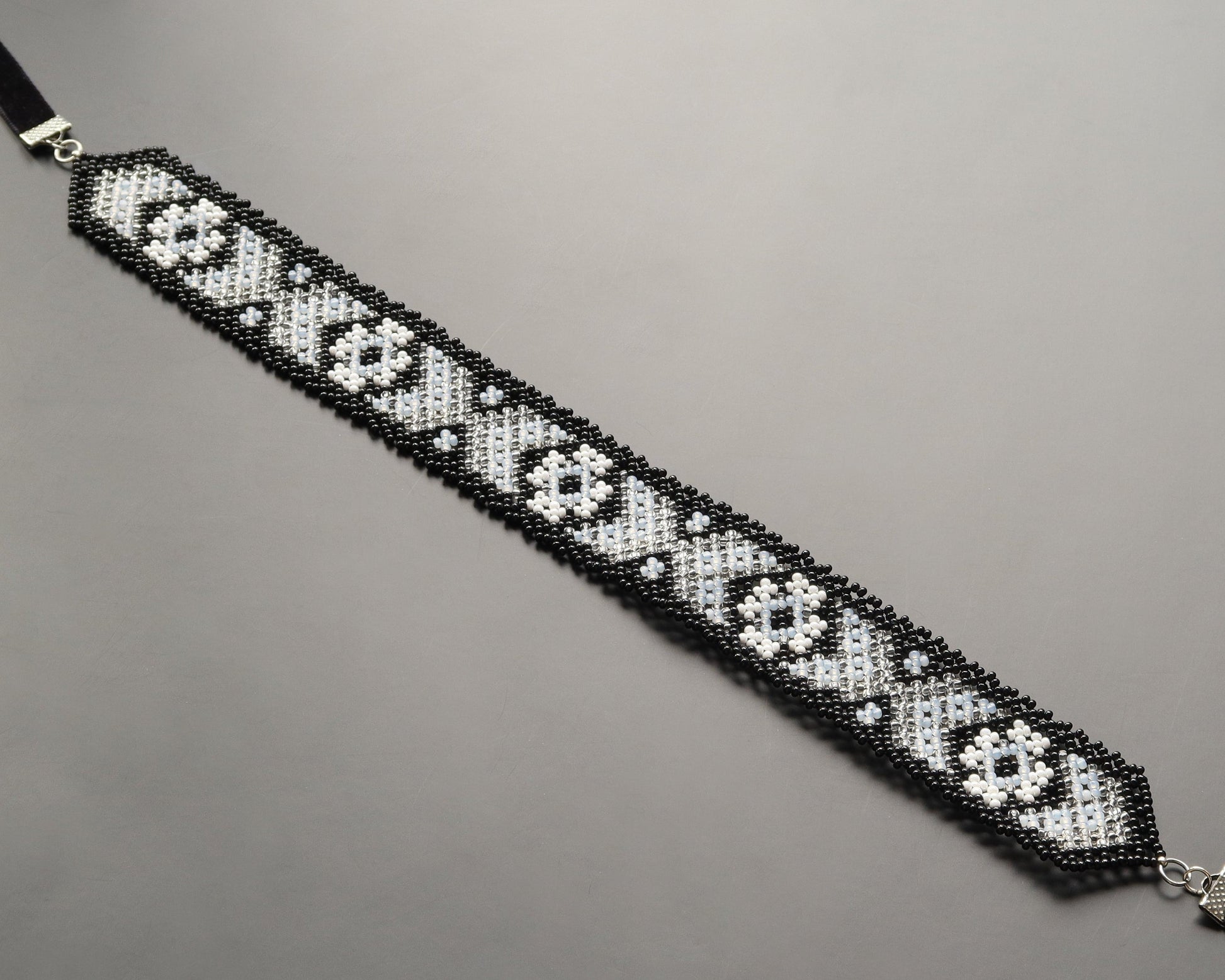 Comely UA Mistweaver gerdan necklace with black, milk, and clear Czech seed beads in a geometric pattern. Adjustable velvet ribbons.