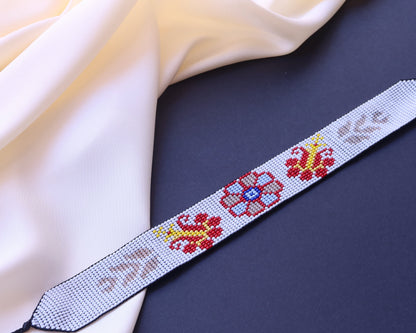 Comely UA white beaded gerdan necklace with red, yellow, blue, and tan floral and leaf motifs. Adjustable ties.