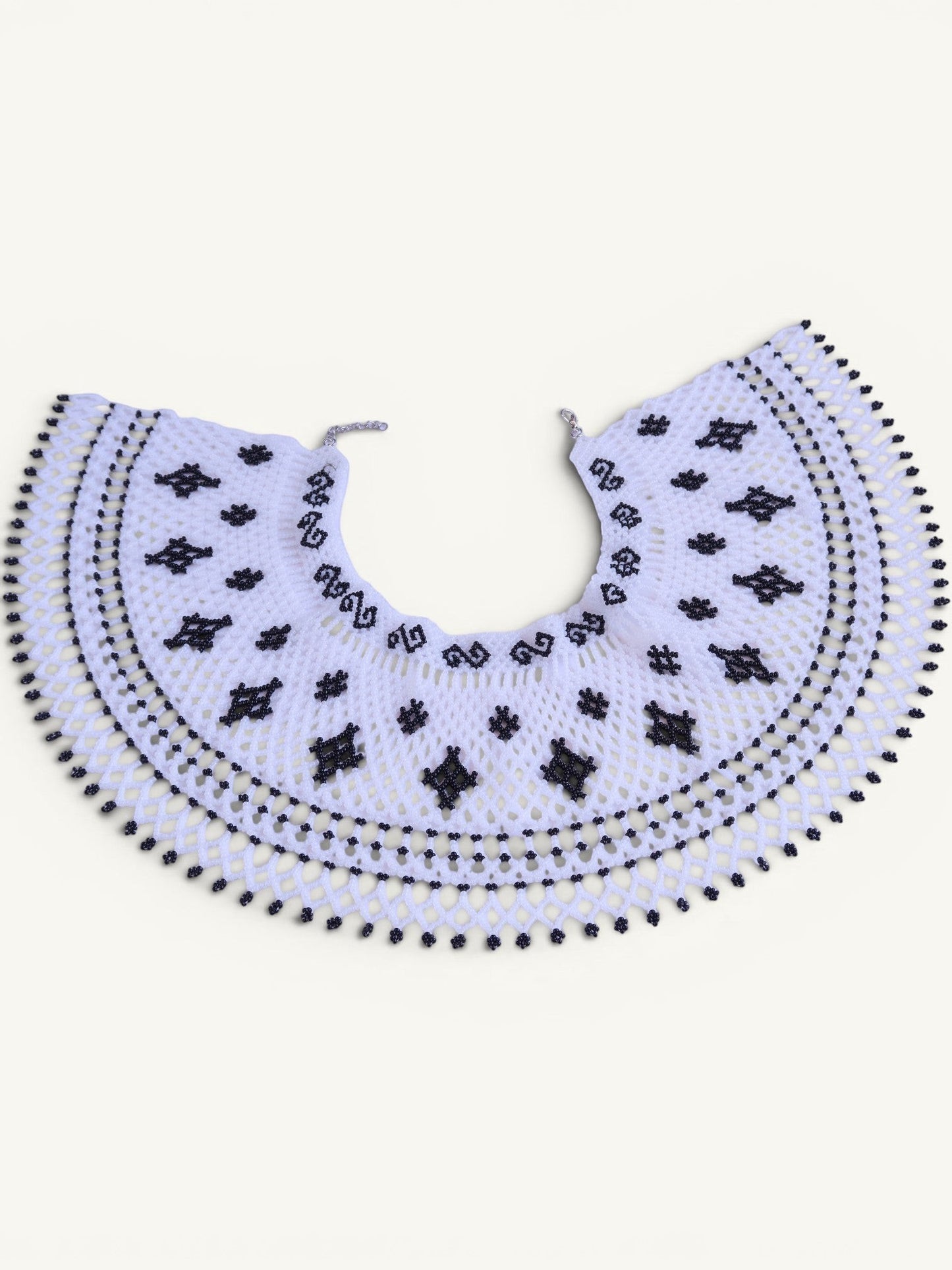 Comely UA Primla beaded necklace in black and white, featuring diamond and cross symbols, with a net-like structure and adjustable clasp.