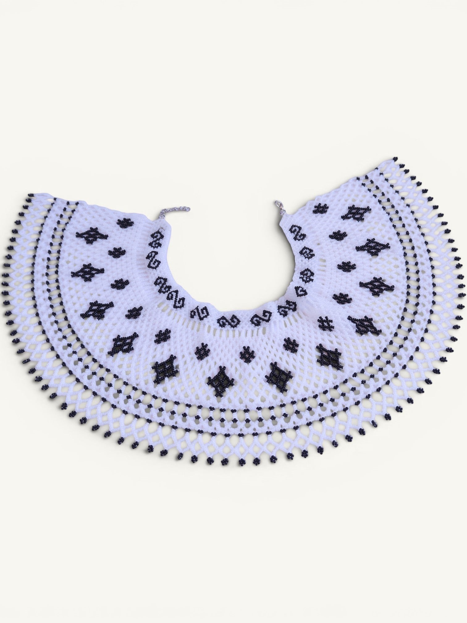 Comely UA Primla beaded necklace in black and white, featuring diamond and cross symbols, with a net-like structure and adjustable clasp.