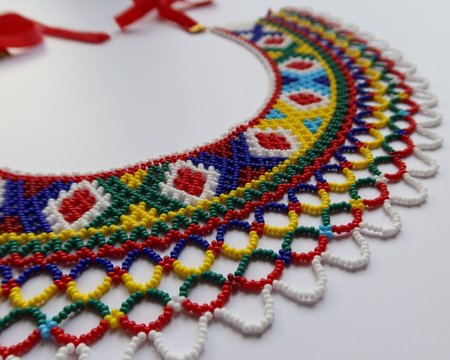 Comely UA Silyanka Lado beaded necklace with diamond and cross motifs in red, blue, yellow, green, and white. Openwork lattice detail.
