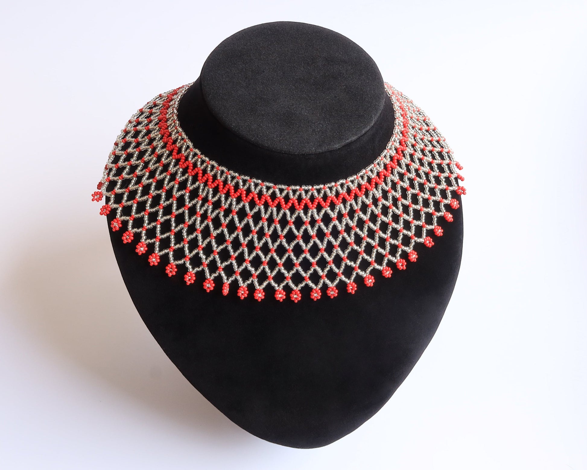 Comely UA Silyanka Solar Crown beaded necklace with red floral accents on a silver web pattern.