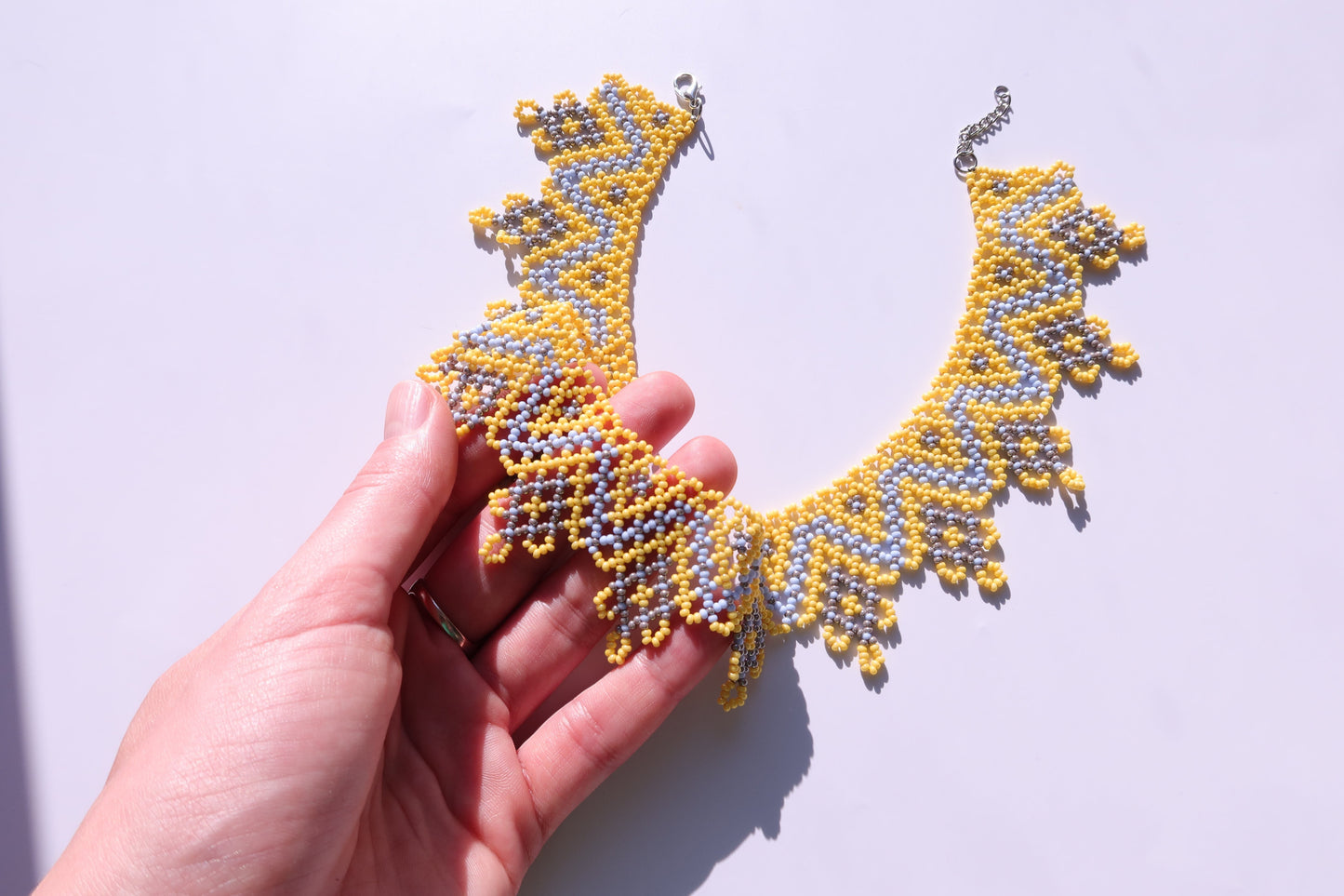 Comely UA Sylianka Zorianytsia beaded necklace in yellow, sky blue, and silver with a jagged wave pattern.