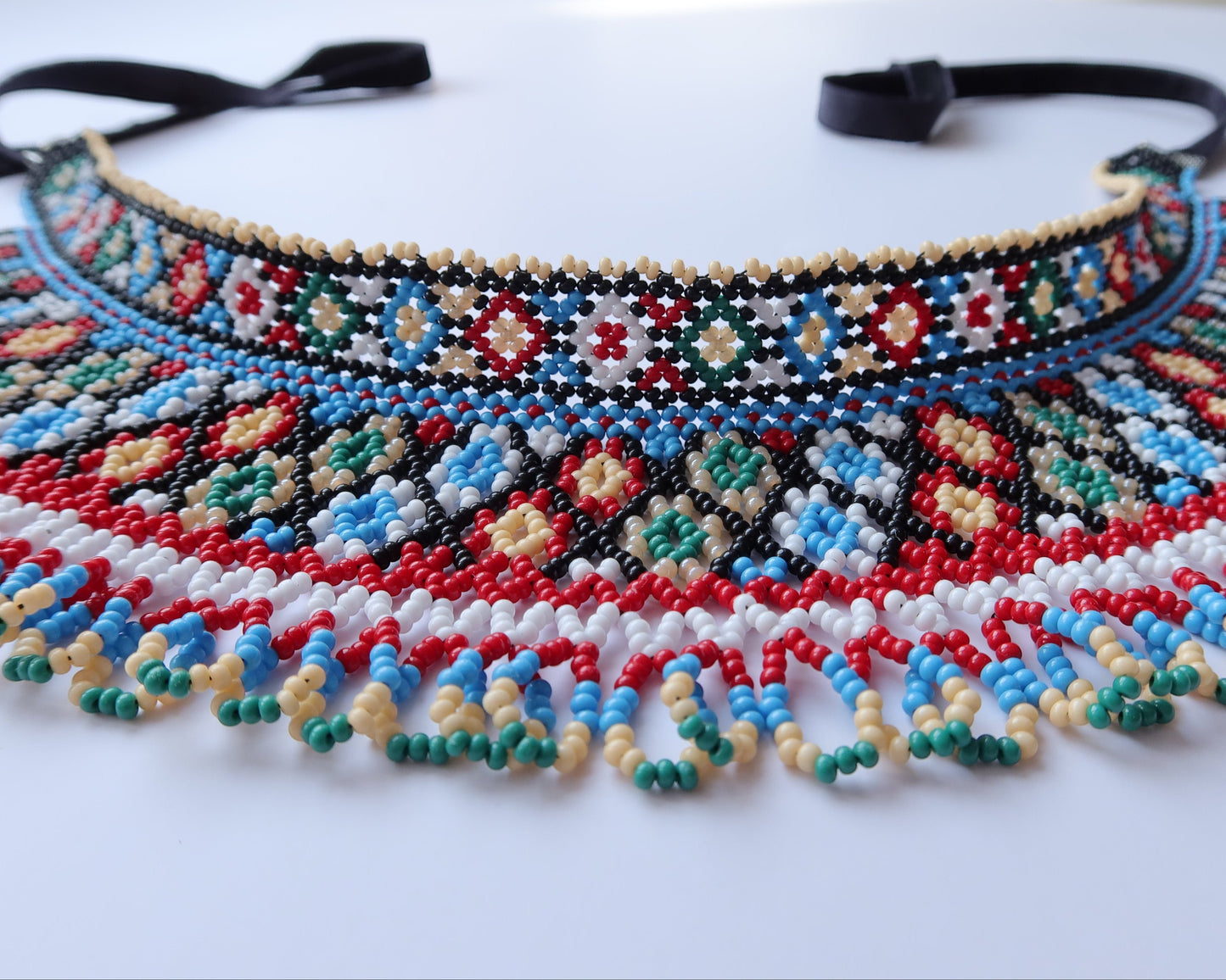 Comely UA two-part beaded necklace with red, black, blue, green, white, and cream Czech seed beads in a net-like structure with diamond motifs.
